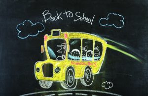 Tea with the Editor Colorful chalk drawing on a blackboard of a yellow school bus with smiling children and a driver, with "Back to School" written above.