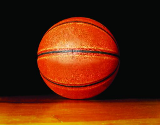 Tallahassee opens registration for fall sports Close-up of an orange basketball resting on a wooden floor against a black background.