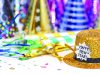 Rings in 2026 at Cascades Park Gold glitter top hat with a “Happy New Year!” label sits on a table surrounded by colorful party hats, streamers, and confetti, suggesting a New Year’s celebration.
