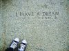 A timeline of notable events in the life of Martin Luther King, Jr. A photograph of engraved stone reading “I HAVE A DREAM – Martin Luther King Jr.”, referencing the March on Washington for Jobs and Freedom on August 28, 1963. The image is framed from above, with a pair of black-and-white sneakers visible at the bottom edge, creating a reflective, symbolic perspective on the historic inscription.