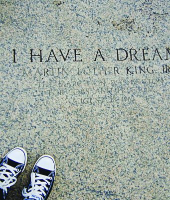 A timeline of notable events in the life of Martin Luther King, Jr. A photograph of engraved stone reading “I HAVE A DREAM – Martin Luther King Jr.”, referencing the March on Washington for Jobs and Freedom on August 28, 1963. The image is framed from above, with a pair of black-and-white sneakers visible at the bottom edge, creating a reflective, symbolic perspective on the historic inscription.