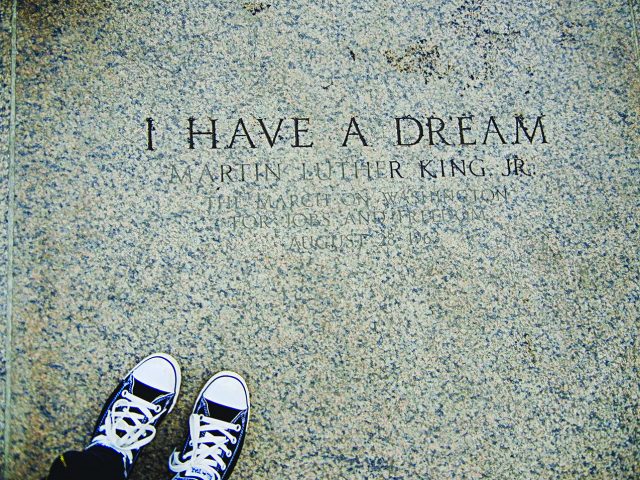 TF251579 A photograph of engraved stone reading “I HAVE A DREAM – Martin Luther King Jr.”, referencing the March on Washington for Jobs and Freedom on August 28, 1963. The image is framed from above, with a pair of black-and-white sneakers visible at the bottom edge, creating a reflective, symbolic perspective on the historic inscription.